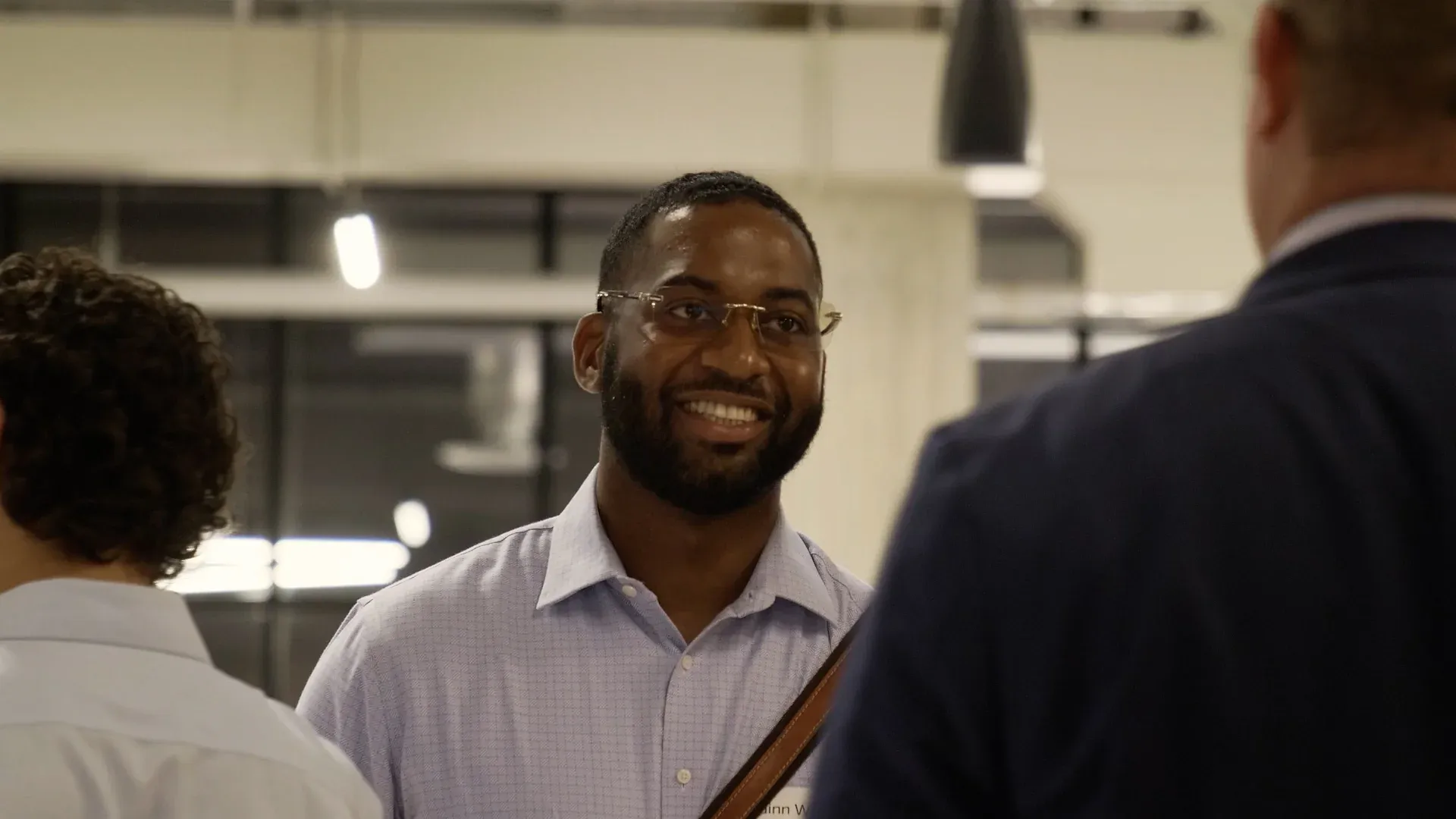 Fervo Energy professional smiling at an investor networking event in an industrial-loft venue, captured for the roadshow film by Motion Giraffx.
