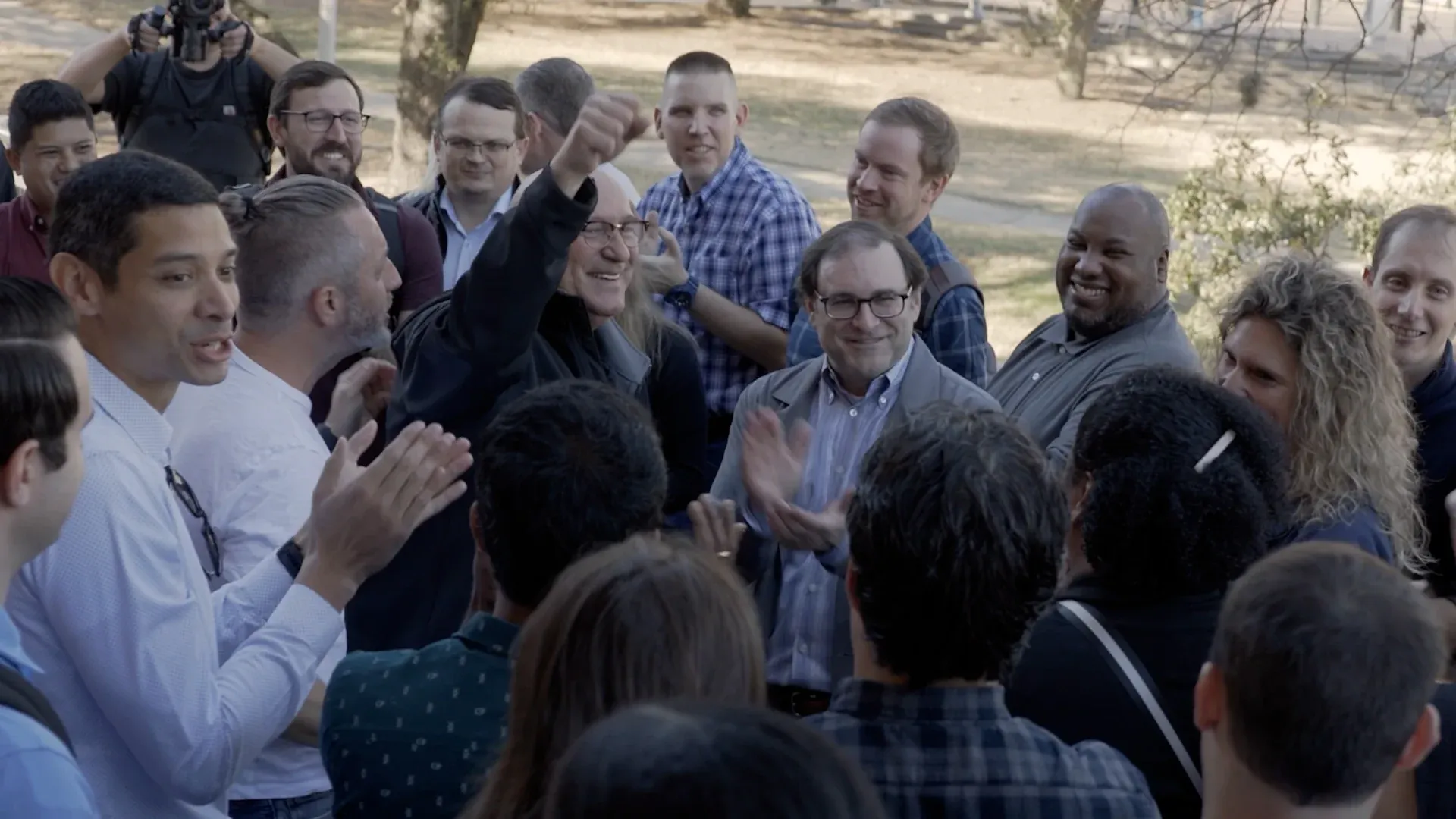 Fervo team member raising a fist mid-cheer surrounded by clapping colleagues outdoors, from the roadshow film by Motion Giraffx.