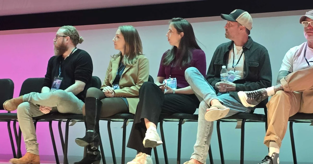 Cara Lackey in a tan blazer, seated second from left on stage at Industry Giants 2026