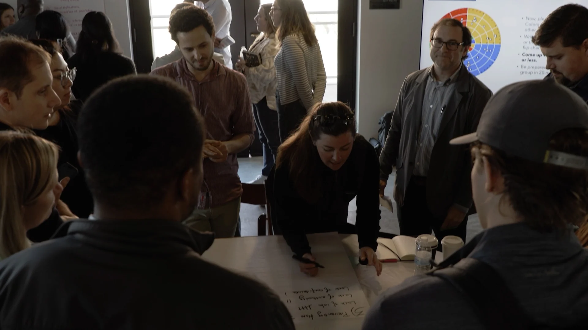 Fervo Energy team in a working session with a colleague writing on a large worksheet, captured by Motion Giraffx.