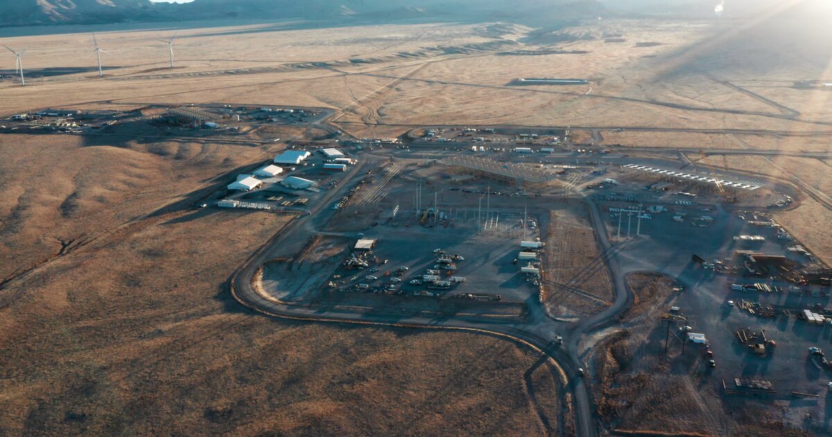 Aerial of Fervo Energy's Cape Station geothermal site at golden hour with wind turbines and the Mineral Mountains on the horizon by Motion Giraffx.